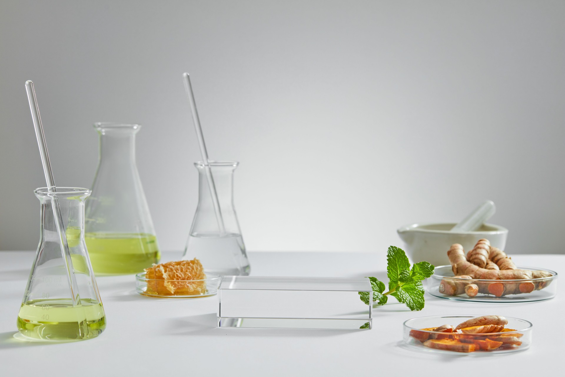 Honey and turmeric decorated with transparent podium and beaker test tube with blank space in white laboratory background for experiment advertising , front view